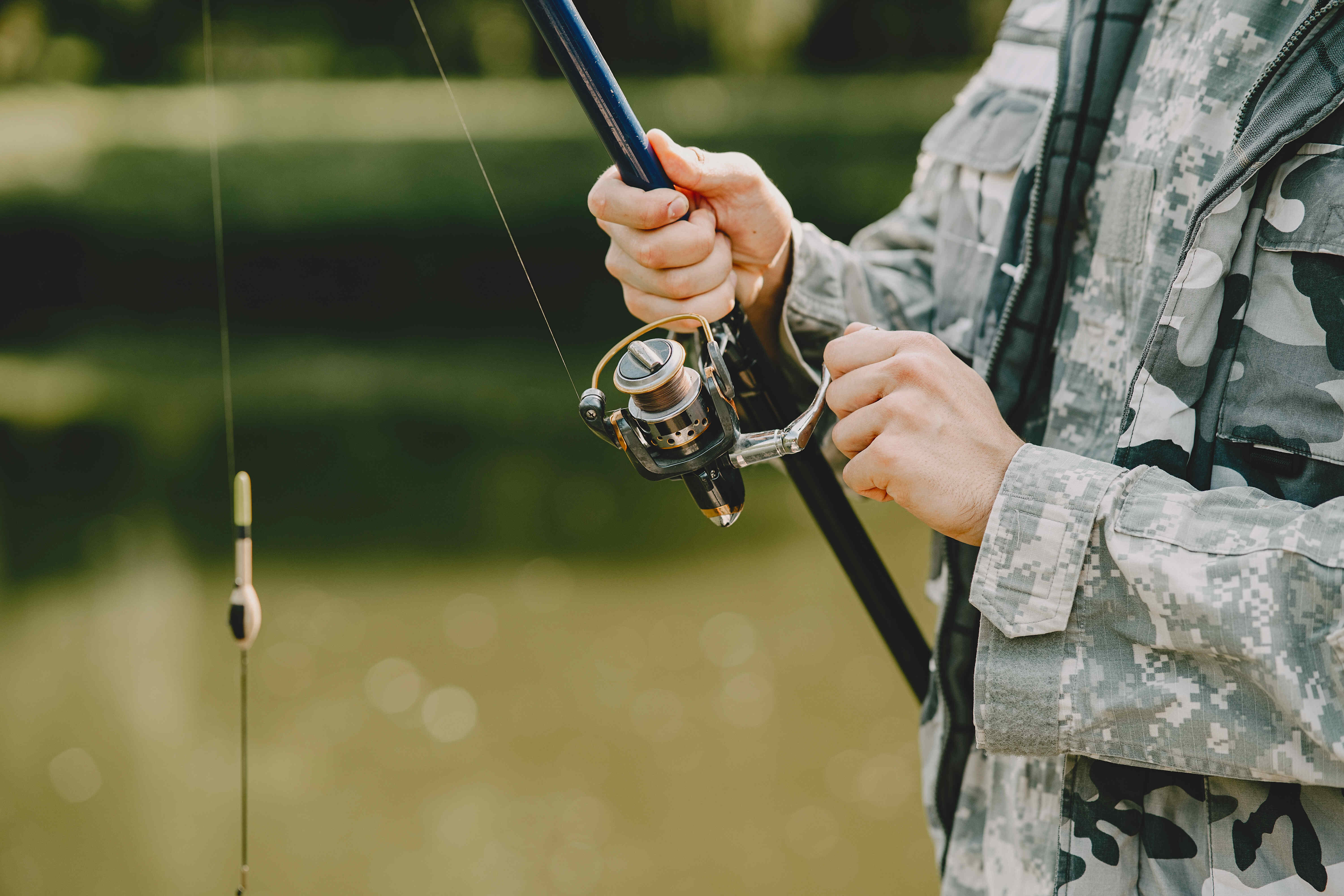 Foto com foco no peito e braço de uma pessoa segurando uma vara de pesca.